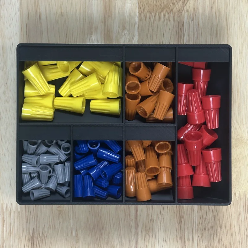 A bin with six compartments of different sizes, each holding one color of wire nuts